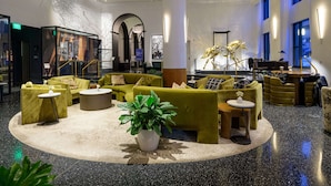 Un vestíbulo espacioso con una zona de estar central, una planta grande en maceta y un candelabro moderno.