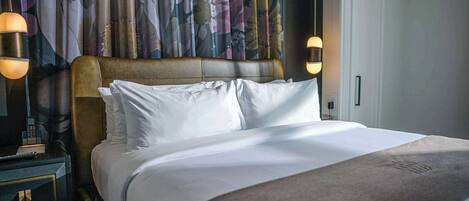 A neatly made bed with white linens, a leather headboard, and two bedside lamps.