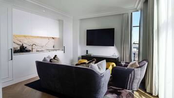 A modern living room with a sofa, a flat-screen TV, and a marble backsplash.