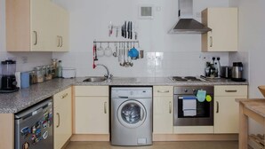 Eine Küche mit Geschirrspüler, Backofen und verschiedenen Küchenutensilien, die an der Wand hängen.