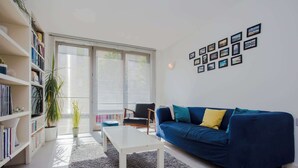 Ein Wohnzimmer mit einem blauen Sofa, einem weißen Couchtisch und einem Bücherregal.