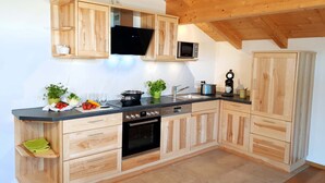 Una cocina moderna con armarios de madera, microondas integrado y cafetera.