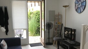 Un salon avec un canapé, un téléviseur, un ventilateur et une horloge au mur.