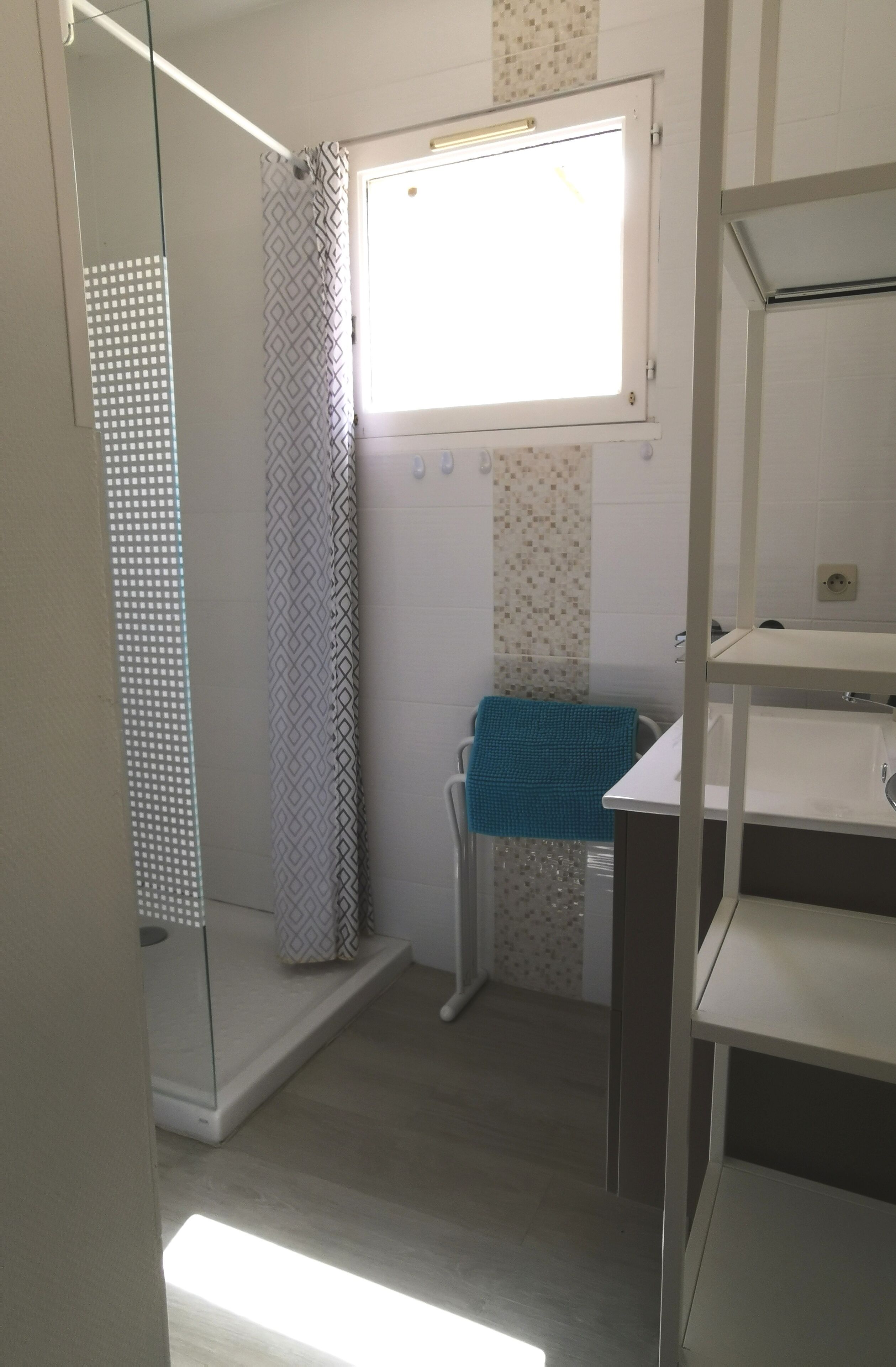 A bathroom with a shower, a sink, and a window.