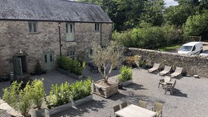 A stone building with a gravel courtyard, outdoor seating, and a stone wall. - Two bedroom stone cottage near Dartmoor and Devon beaches (Ashburton)