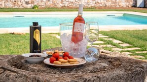 A bottle of wine, ice, glasses, a bottle of Stornelli, and snacks on a stone table by a pool. - Borgo Santuri (Ostuni)