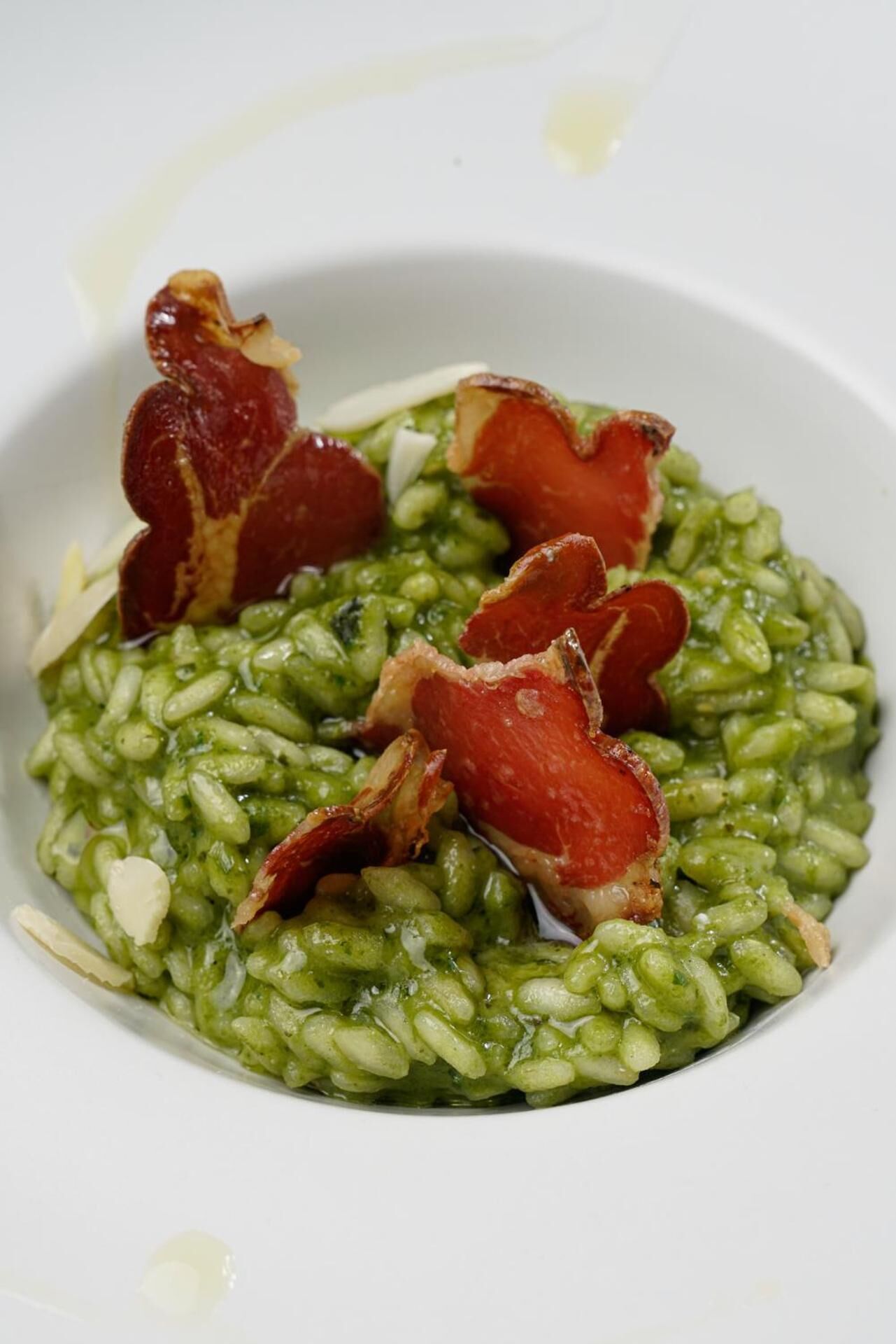 Un bol de risotto vert, garni de morceaux de lardons.