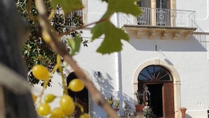 A building with a white facade, arched doorways, and a balcony with metal railings. - Borgo Santuri (Ostuni)