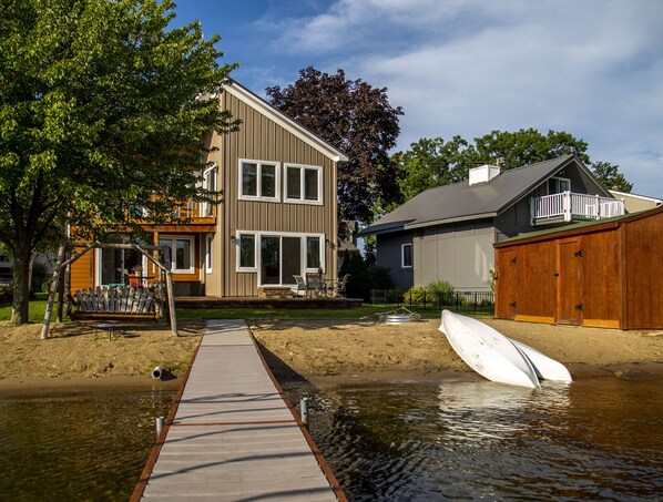 A residential area with a wooden dock leading to a house with a balcony and a garage.