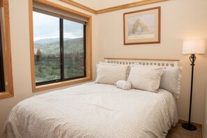 A bedroom with a large window, a framed picture on the wall, and a bedside lamp. - 2 Minute Walk to Slopes/Hot Tub Access/Private Patio (Keystone)