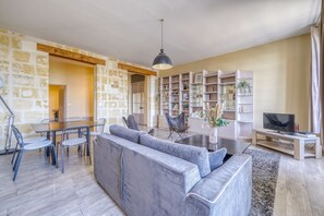 A modern living room with a sofa, dining table, chairs, and a TV. - LE RICHELIEU - Magnifique duplex avec une vue Incroyable (Bordeaux)