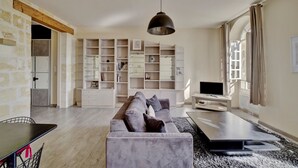 A modern living room with a grey sofa, a TV, and a large bookshelf. - LE RICHELIEU - Magnifique duplex avec une vue Incroyable (Bordeaux)