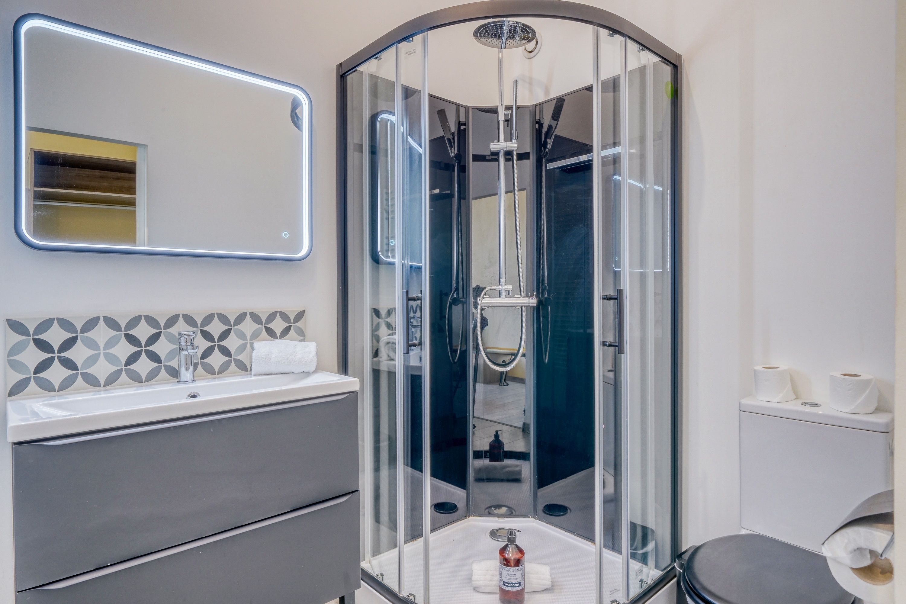 Une salle de bain moderne avec une douche à parois de verre, un meuble-lavabo avec un miroir et des toilettes.