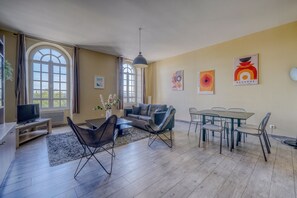 A spacious living area with a sofa, chairs, a dining table, and artwork on the walls. - LE RICHELIEU - Magnifique duplex avec une vue Incroyable (Bordeaux)