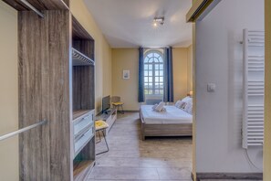 A hotel room with a bed, a desk with a chair, a window with curtains, and a wooden wardrobe. - LE RICHELIEU - Magnifique duplex avec une vue Incroyable (Bordeaux)