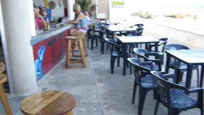 Un café en plein air avec des tables et des chaises, un coin bar et une fresque murale.