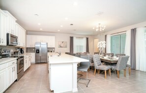 Una cocina moderna con gabinetes blancos, electrodomésticos de acero inoxidable y una isla central.