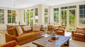 Ein geräumiges Wohnzimmer mit einem großen braunen Ledersofa, einem Holztisch und einem Essbereich mit Tisch und Stühlen.