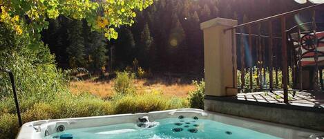 A hot tub with a view of a forested area and a building in the background.