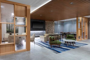 A modern living room with a stone accent wall, a flat-screen TV, and a wooden ceiling. - Fairfield Inn & Suites by Marriott Atlanta Marietta (Marietta)