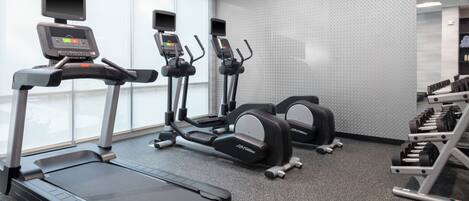 Una palestra con tapis roulant, ellittiche e macchinari per l'allenamento con i pesi.