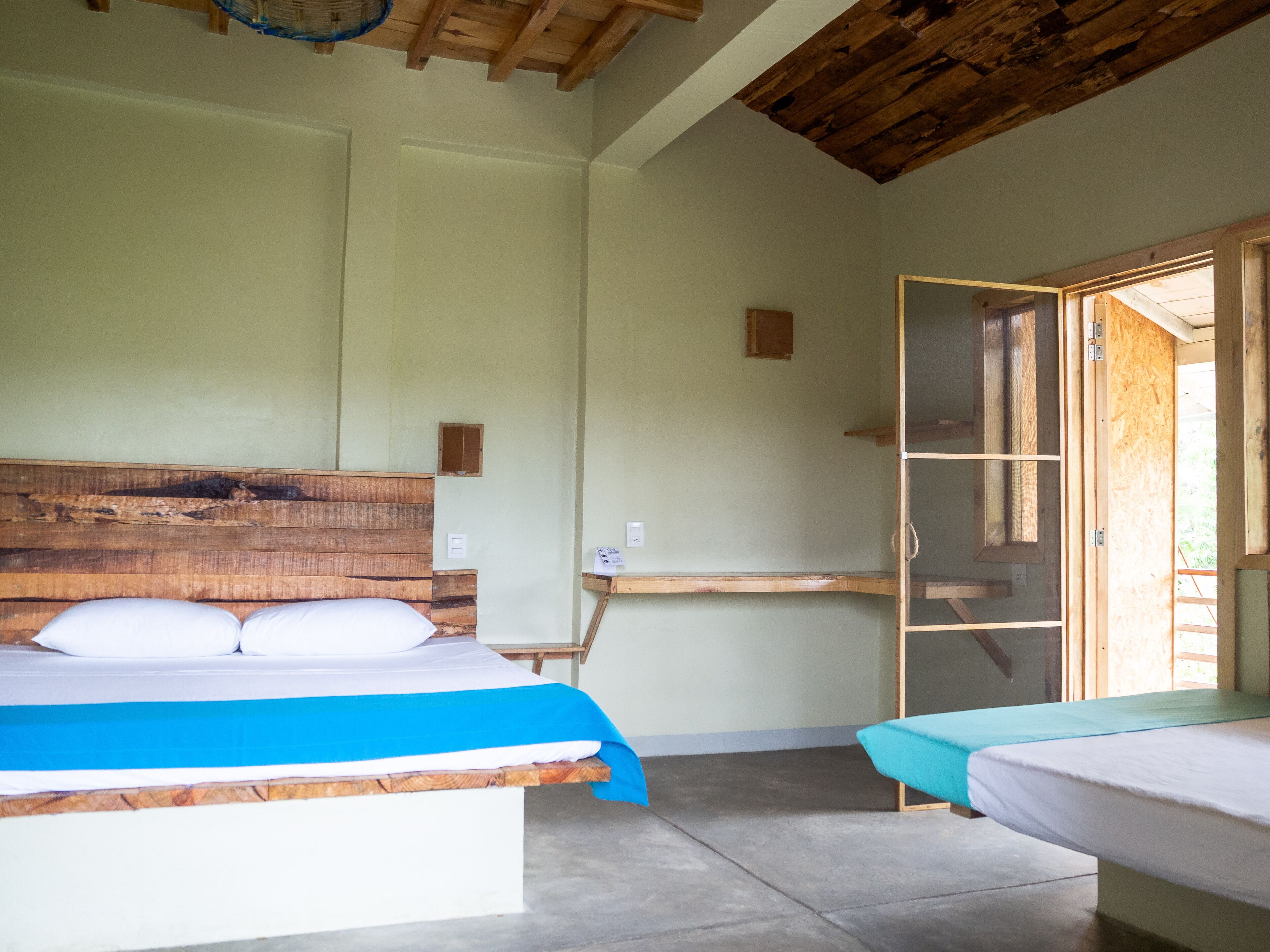 A room with a wooden headboard bed, a small bedside table, and a window with a view.