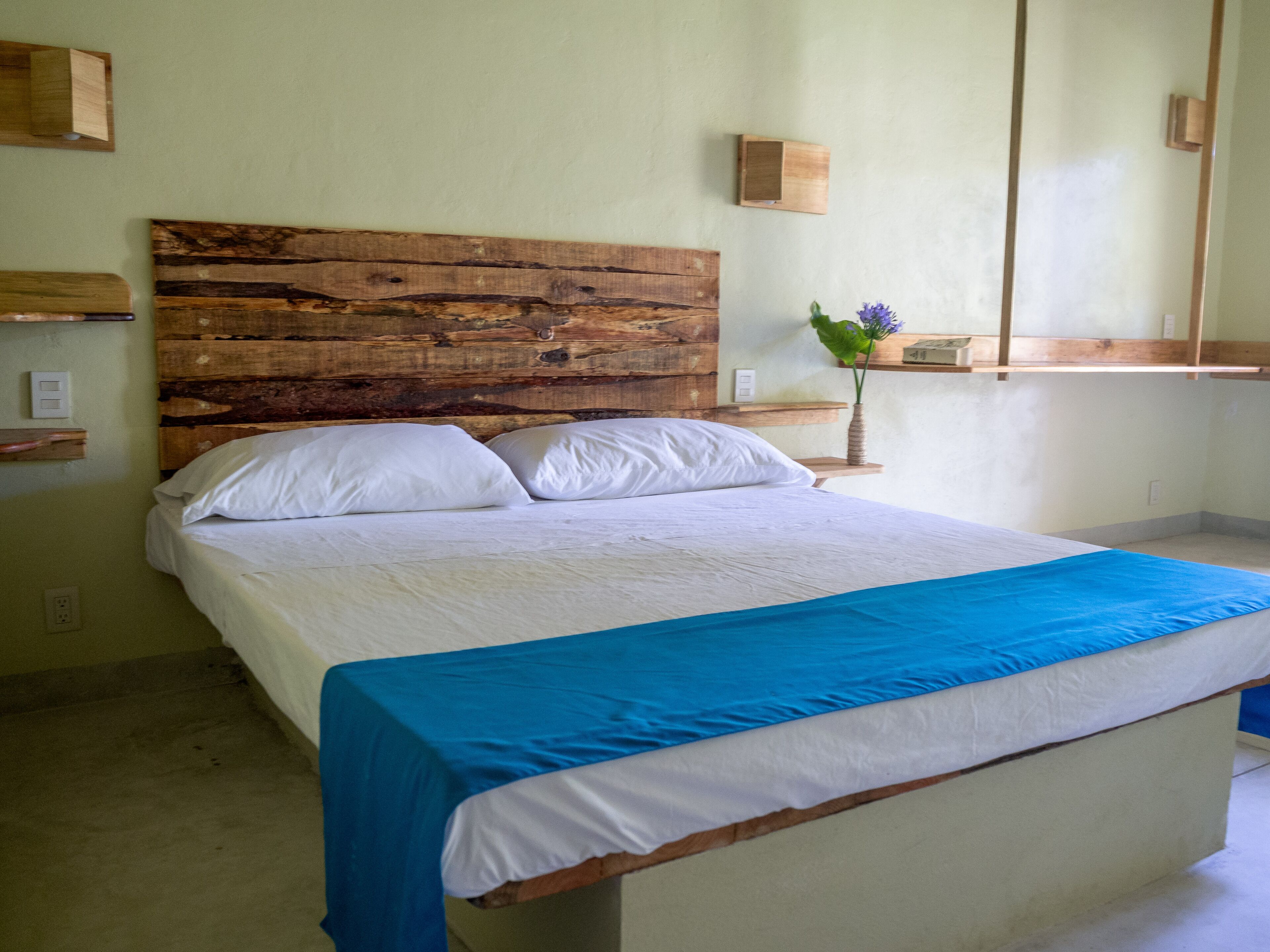 A bed with a wooden headboard, white bedding, and a blue accent.