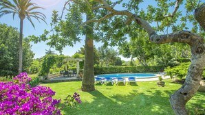 A pool area with lounge chairs, surrounded by lush greenery and flowering plants. - 3 Bedrooms, 2 bathrooms, enbeded into the natural mediterranean surrounding. (Pollença)