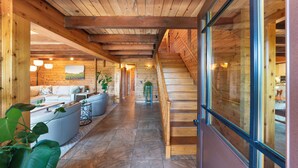 A wooden interior with a staircase, a sofa, and a dining area.