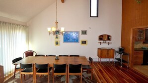 Un comedor con una mesa y sillas de madera, una araña y cuadros enmarcados en la pared.
