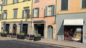 A street with buildings, including a restaurant named 'Mr. KITA' and a shop with a large advertisement. - Little Suite Bergamo (Bergamo)