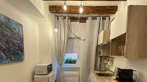 A compact kitchen with a washing machine, a dining area with a table and chairs, and a window with curtains. - Little Suite Bergamo (Bergamo)