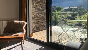 A room with a stone wall, a wooden deck, and a view of mountains.