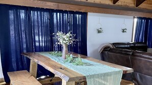 A rustic wooden dining table with benches, a vase with flowers, and a blue curtain backdrop. - TRI-LEVEL HOUSE WITH HUGE DECK AND AMAZING VIEWS OF THE BLACK HILLS (Custer)