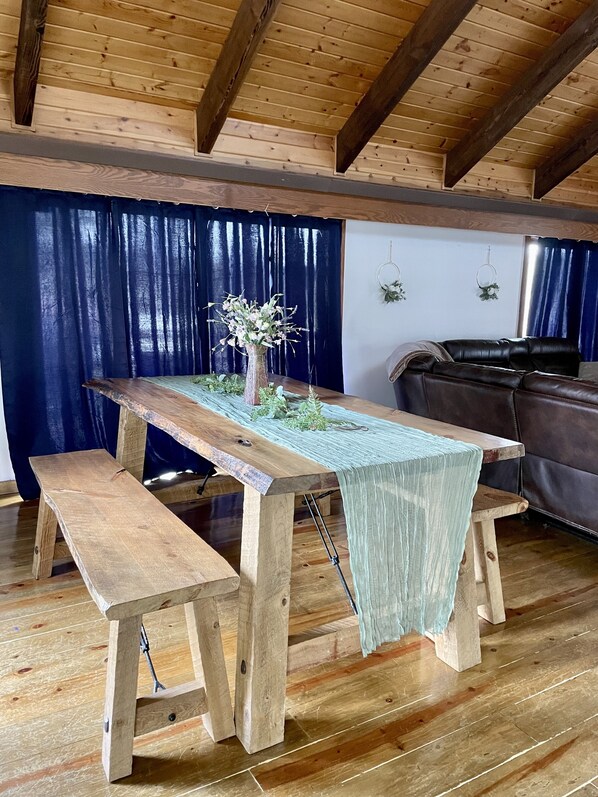 Una mesa de madera rústica con bancos, un jarrón con flores y un telón de fondo azul.
