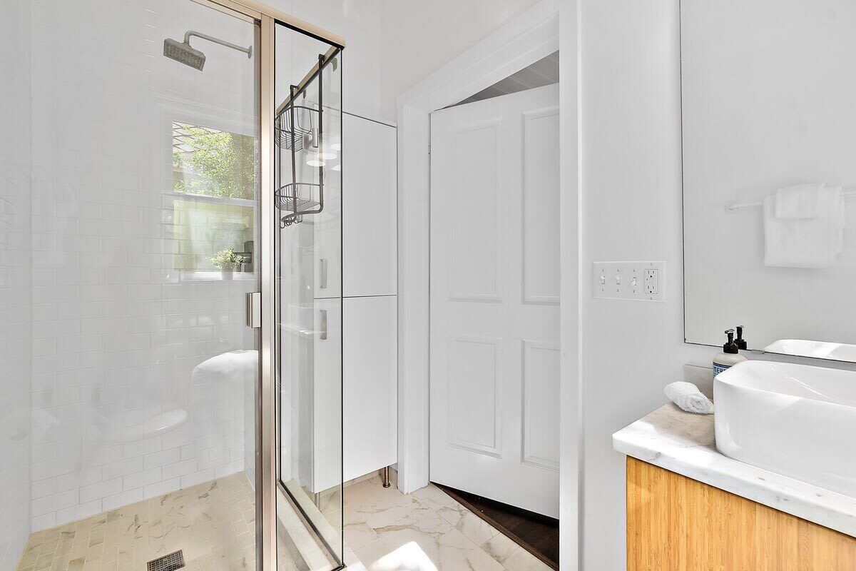 Une salle de bain moderne avec une douche à parois de verre, un lavabo blanc et un meuble-lavabo en bois.