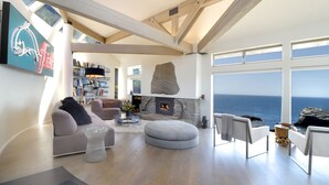 Ein geräumiges Wohnzimmer mit Kamin, einem großen Stein-Akzent und Meerblick.