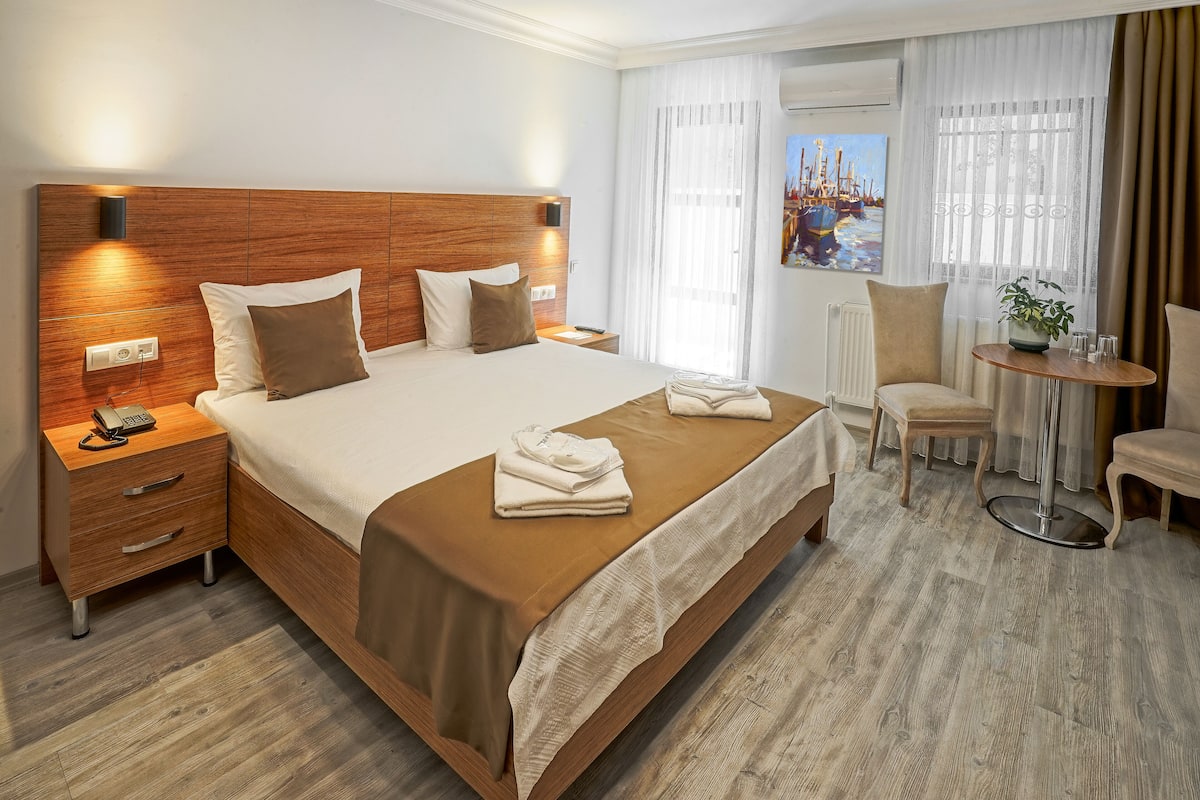 A hotel room with a large bed, bedside tables, a desk, and a chair.