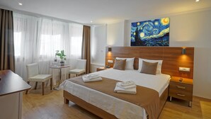 Habitación de hotel con una cama grande, mesitas de noche, un escritorio y una silla.
