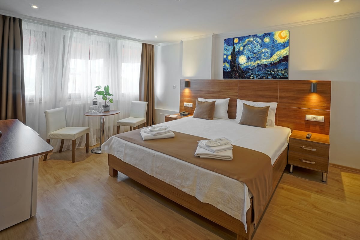 A hotel room with a large bed, bedside tables, a desk, and a chair.