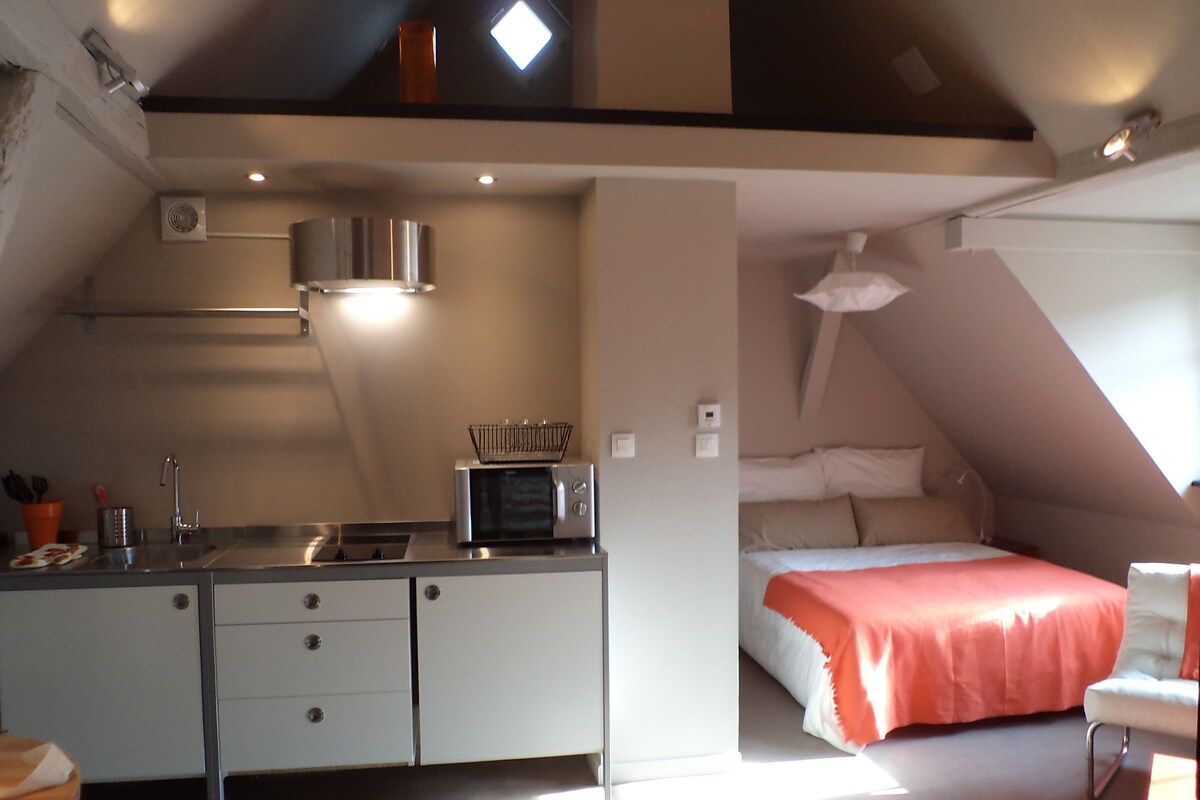 Ein kleines Zimmer mit Küchenzeile, einem Bett und einer kleinen Sitzecke.