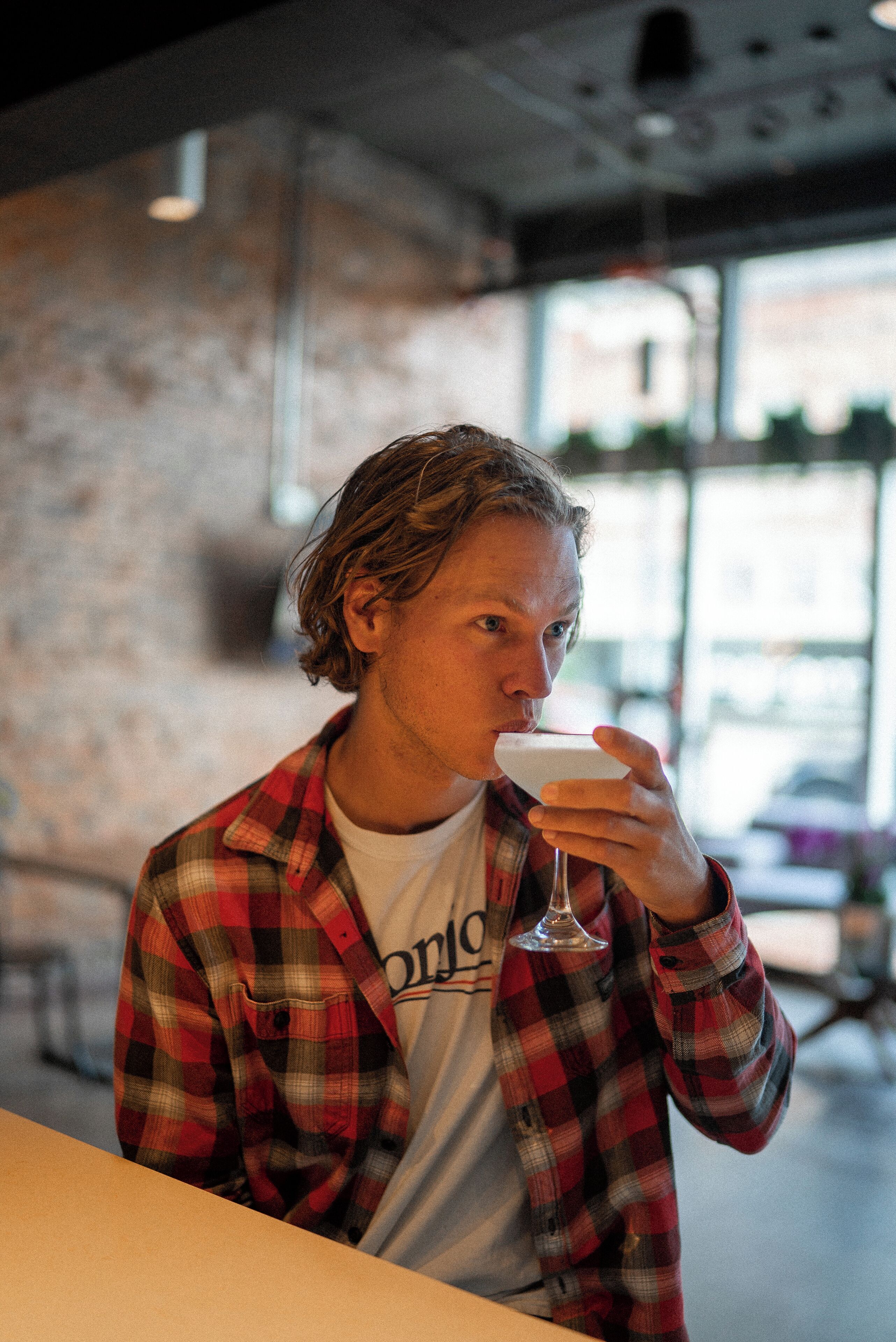 Une personne portant une chemise à carreaux et tenant un verre.