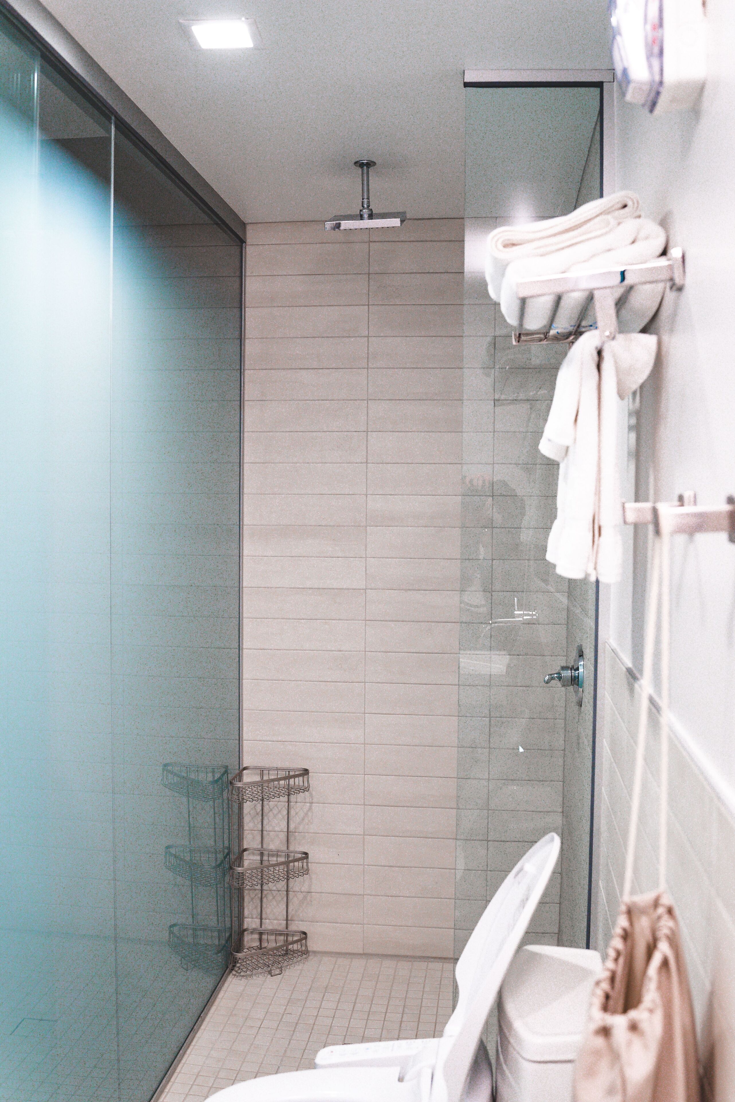 Un baño moderno con cabina de ducha de vidrio, inodoro y perchero.