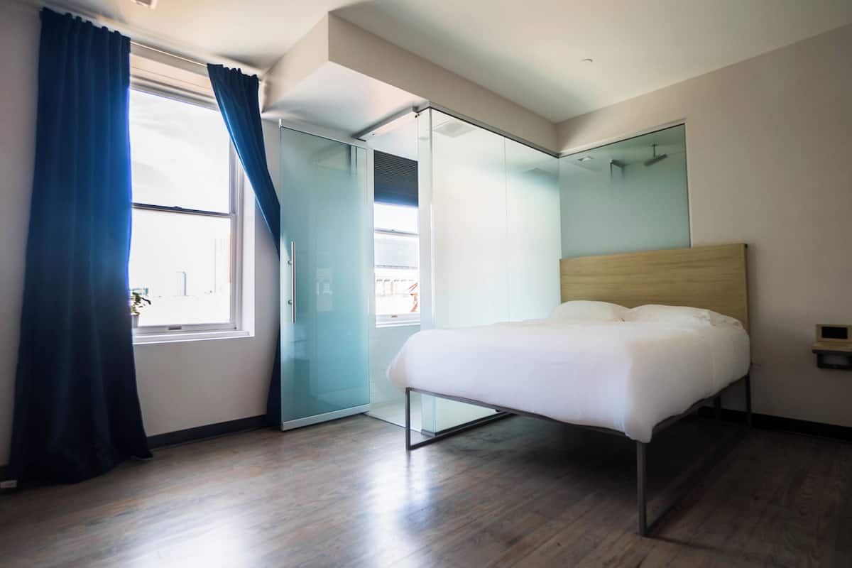 A modern bedroom with a bed, a sliding glass door, and a large window with curtains.