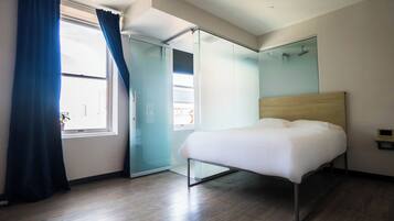 A modern bedroom with a bed, a sliding glass door, and a large window with curtains.