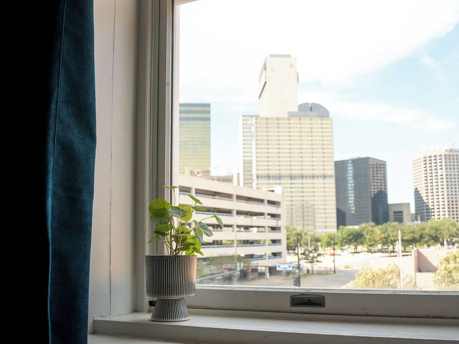 Una ventana con vista a un paisaje urbano, que incluye edificios altos y un estacionamiento.