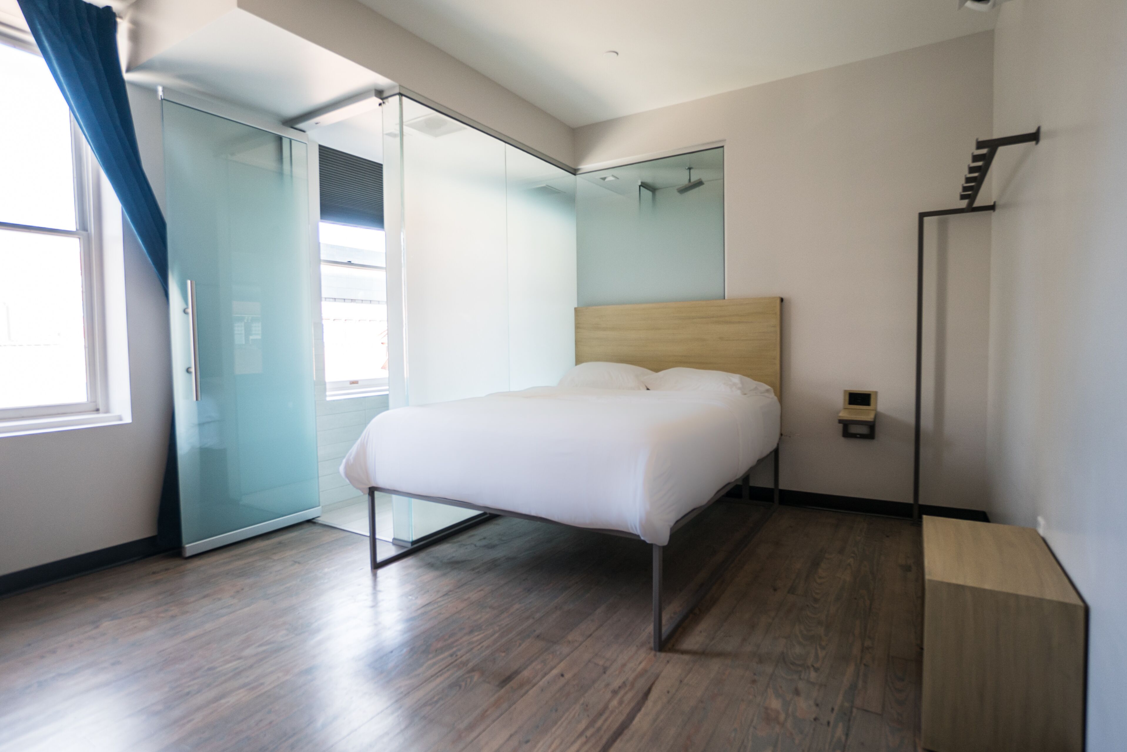 Una habitación de hotel moderna con una cama, un cristalero que da a un balcón y suelo de madera.