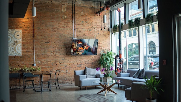 A modern interior with a brick wall, a flat-screen TV, seating area, and large windows.