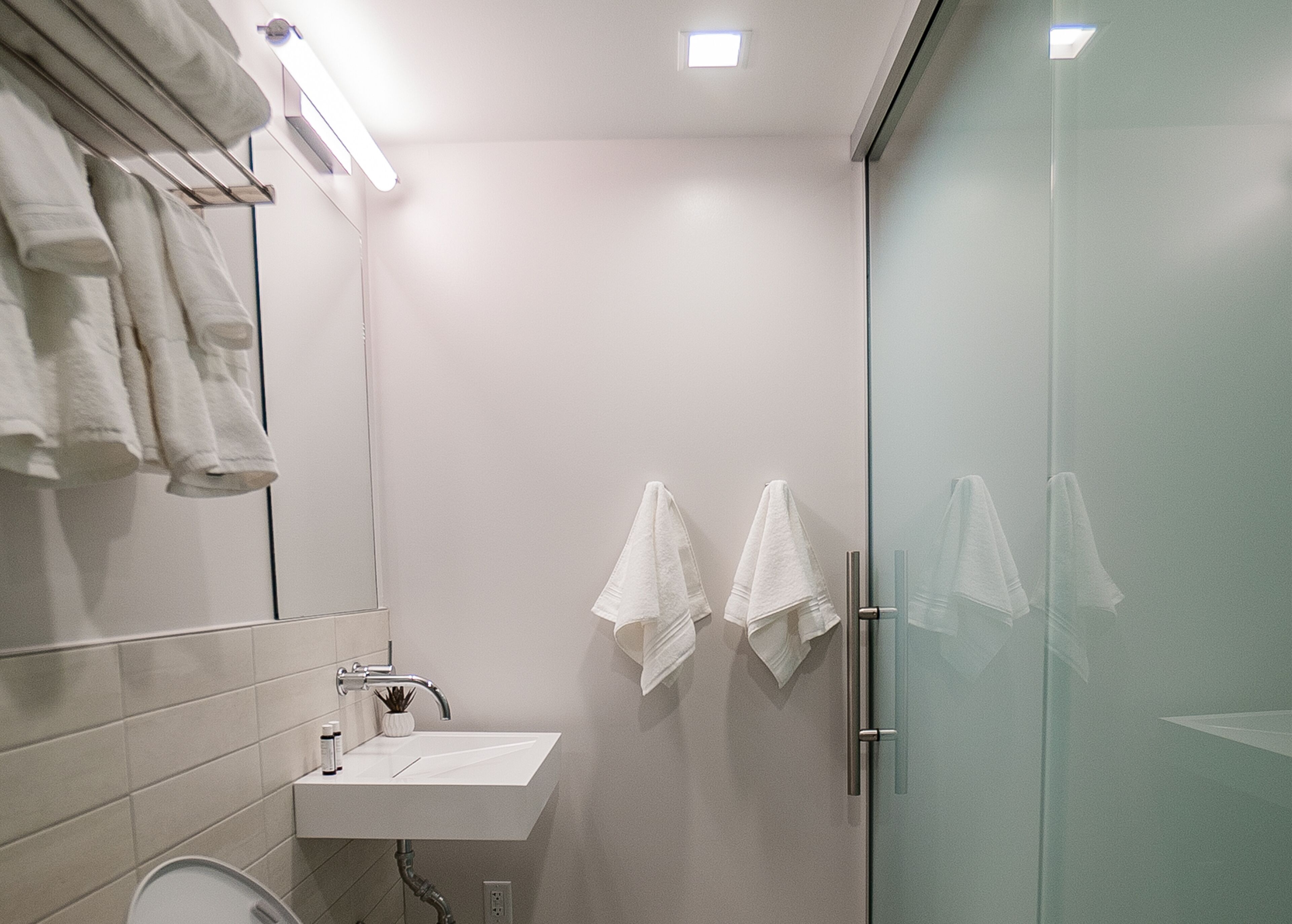 A modern bathroom with a white sink, a mirror, and a glass shower enclosure.