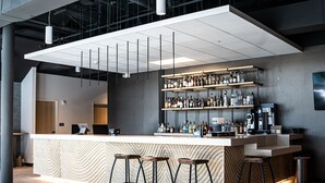 A modern bar area with a counter, stools, and shelves of bottles.